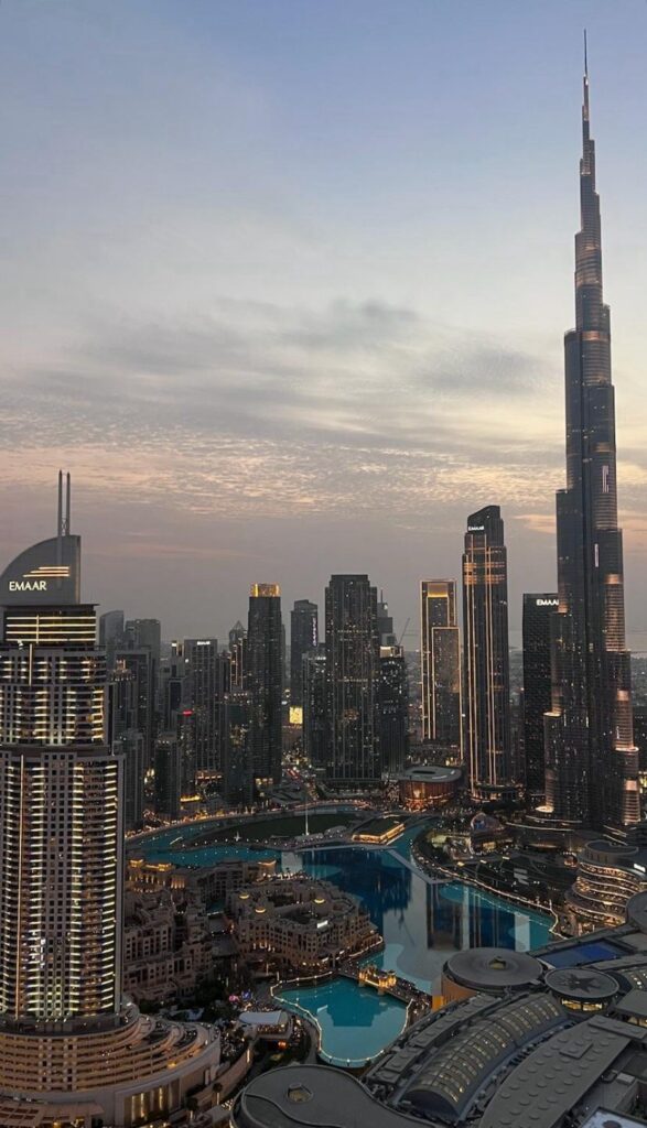 Twilight view of Downtown Dubai skyline featuring Burj Khalifa and EMAAR towers beside turquoise lake